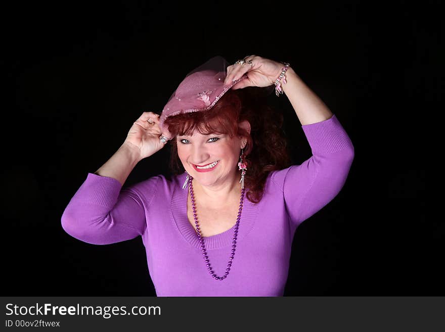 Beautiful red head woman wearing a pink hat isolated on black background. Beautiful red head woman wearing a pink hat isolated on black background