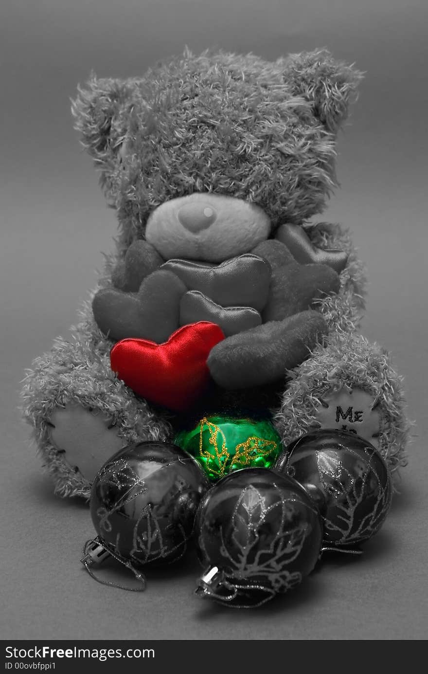 A teddy bear holding hearts in his hands, one highlighted red, with one green ball in front. A teddy bear holding hearts in his hands, one highlighted red, with one green ball in front.