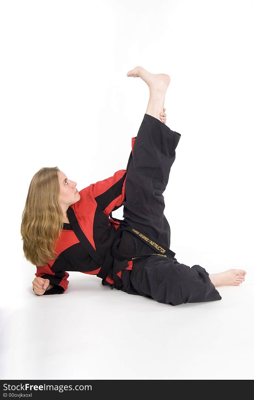 Female martial artist in red and black uniform stretching. Female martial artist in red and black uniform stretching.