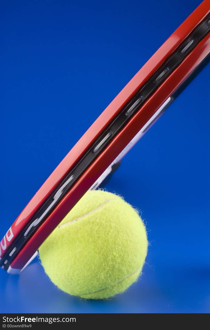 Tennis ball is next to a part of a tennis racket