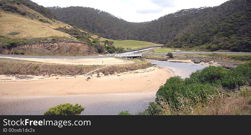 Bridge over small river leading to sea and with green background. Bridge over small river leading to sea and with green background