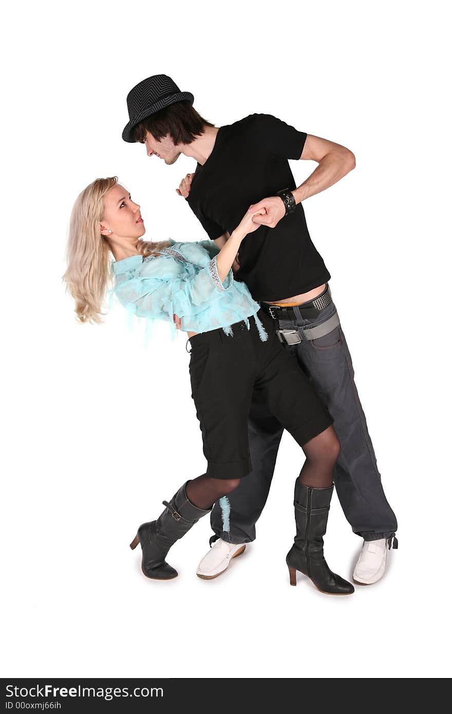 Girl in cyan blouse dances with boy in black hat on white