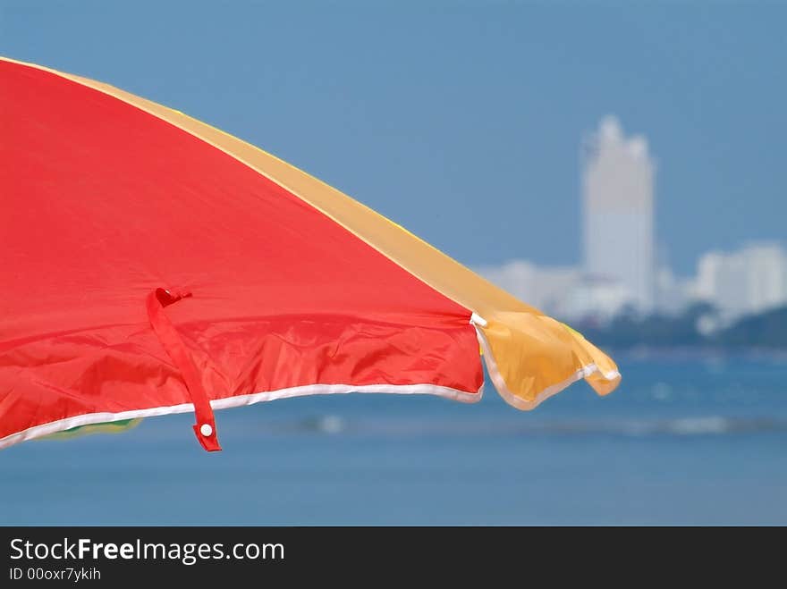 Detail of parasol at the beach with a white building in the background. The building is strongly out of focus. Detail of parasol at the beach with a white building in the background. The building is strongly out of focus.