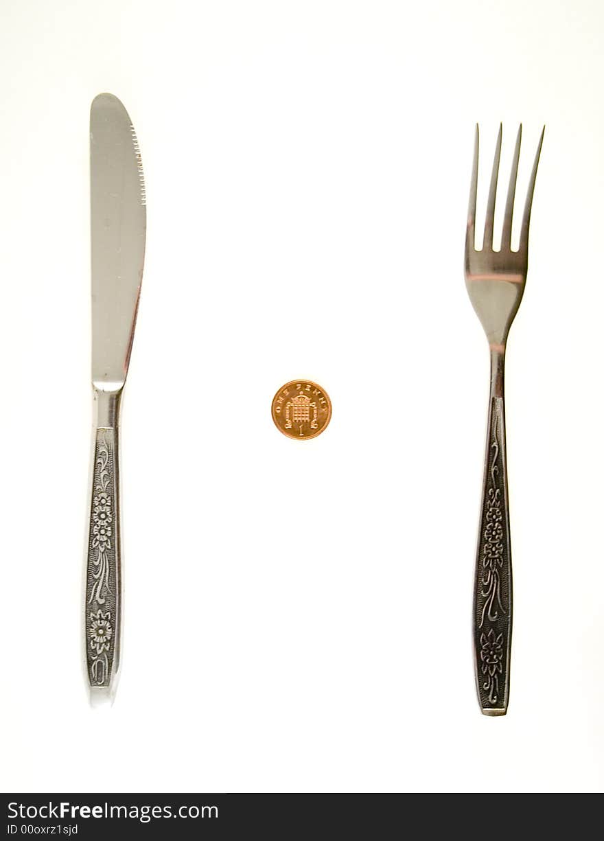 One penny lying between fork and knife. One penny lying between fork and knife