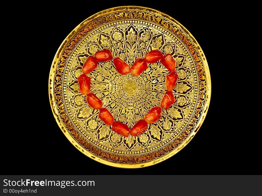 Small round brass tray with a pattern and heart made of pomegranate's grains. Small round brass tray with a pattern and heart made of pomegranate's grains