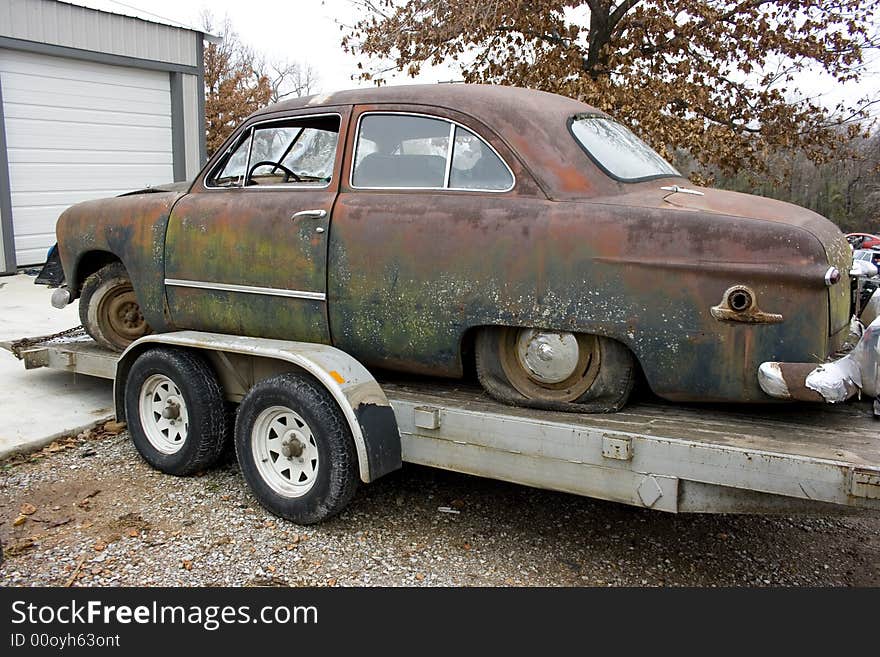 1949 Ford two door sedan awaiting restoration.  Side view of a blue green sedan with a and rust patina. 1949 Ford two door sedan awaiting restoration.  Side view of a blue green sedan with a and rust patina.