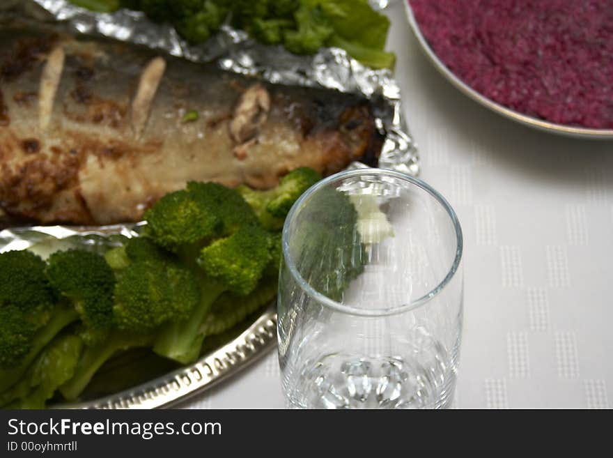 Close-up of baked pink salmon served with broccoli at served table with plates and christal glass. Close-up of baked pink salmon served with broccoli at served table with plates and christal glass