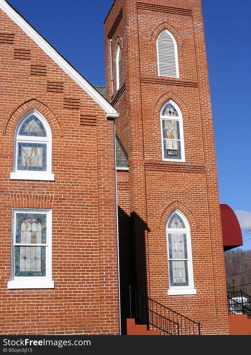 An Arched stained glass window in a brick church with great architectural design. An Arched stained glass window in a brick church with great architectural design.