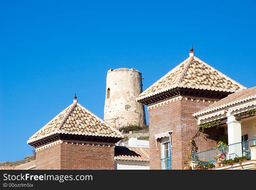 Front building towers with spanish defensive tower in background. Front towers covered in andalusian style. Front building towers with spanish defensive tower in background. Front towers covered in andalusian style.