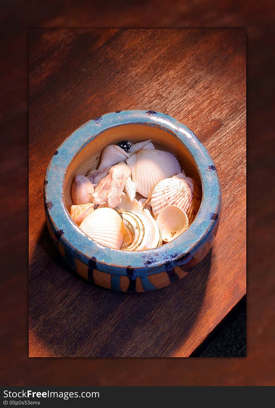 A ceramic bowl of seashells on a wooden table