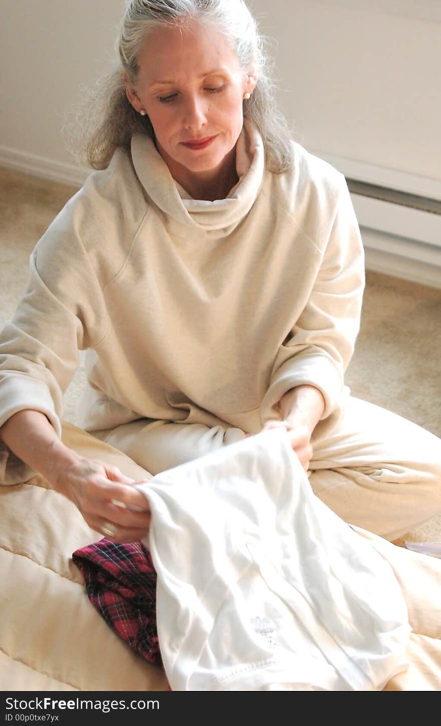 Woman folding clothes in her bedroom. Woman folding clothes in her bedroom.