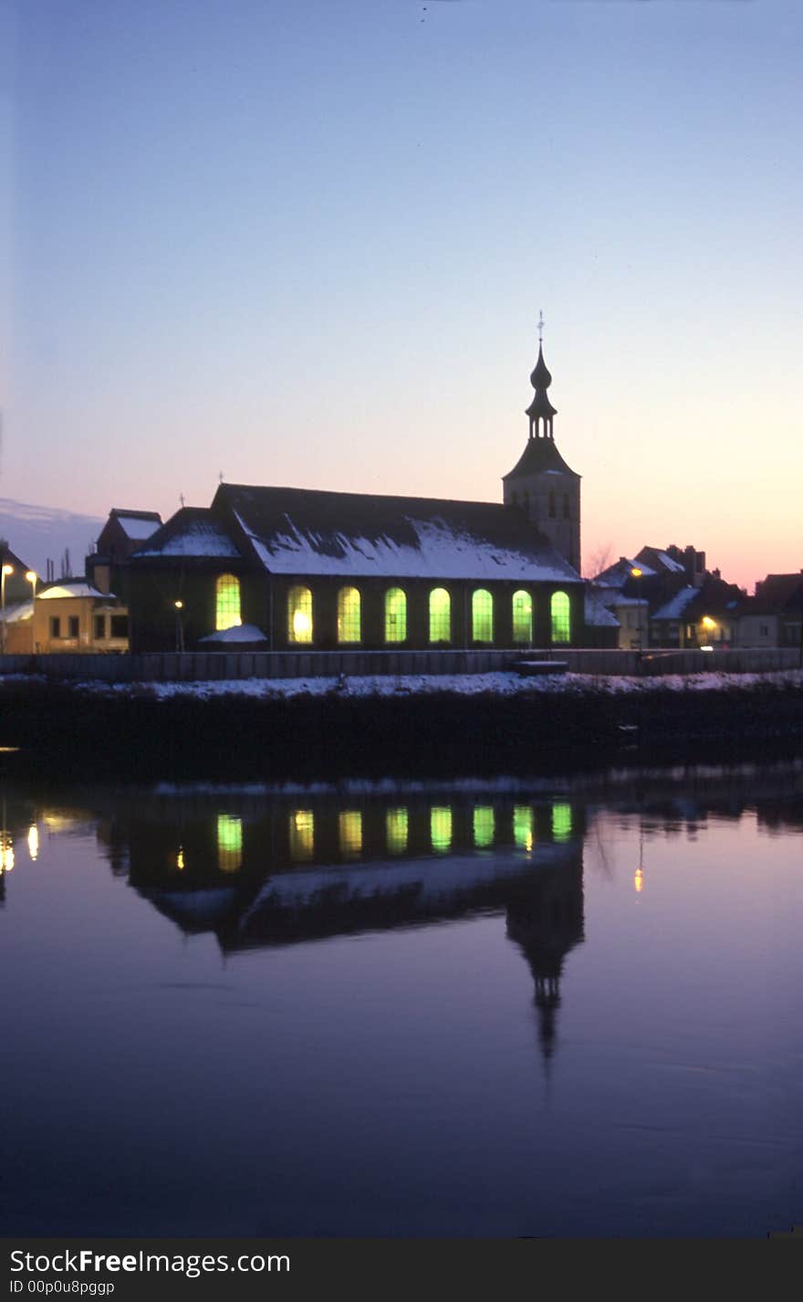 Small church at christmas time close to border river, reflection of the lights in the water at night time. Small church at christmas time close to border river, reflection of the lights in the water at night time