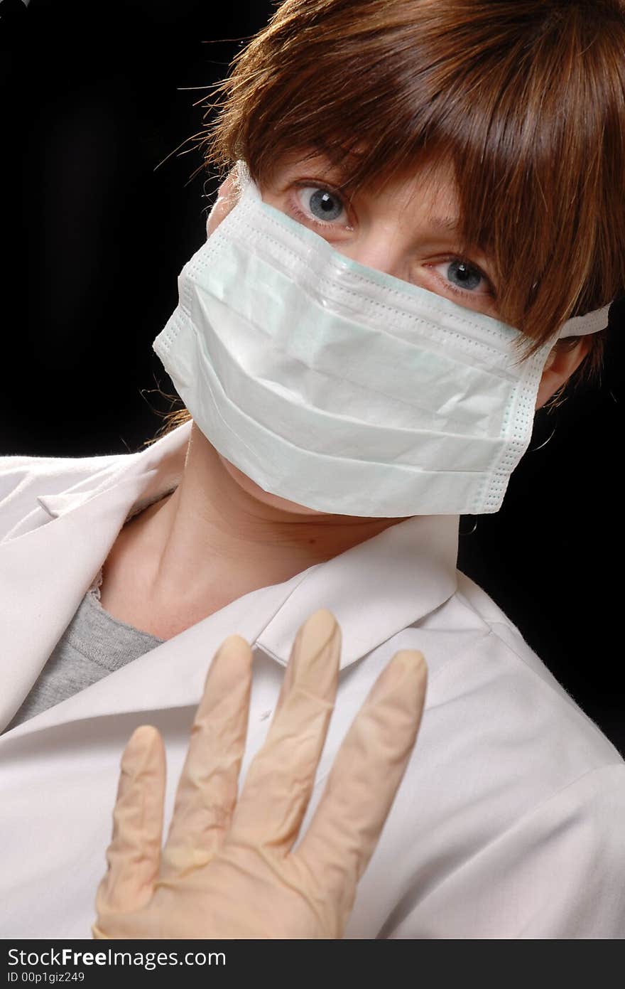 Attractive young lady doctor in white coat with face mask - on black background. Attractive young lady doctor in white coat with face mask - on black background