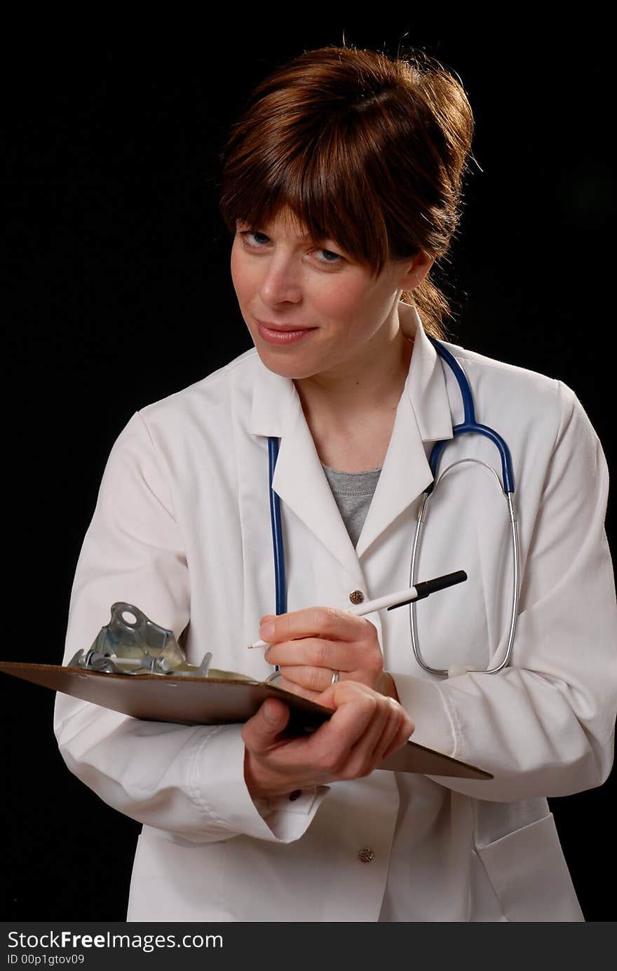 Attractive young lady doctor in white coat with stethosope making notes - on black background. Attractive young lady doctor in white coat with stethosope making notes - on black background