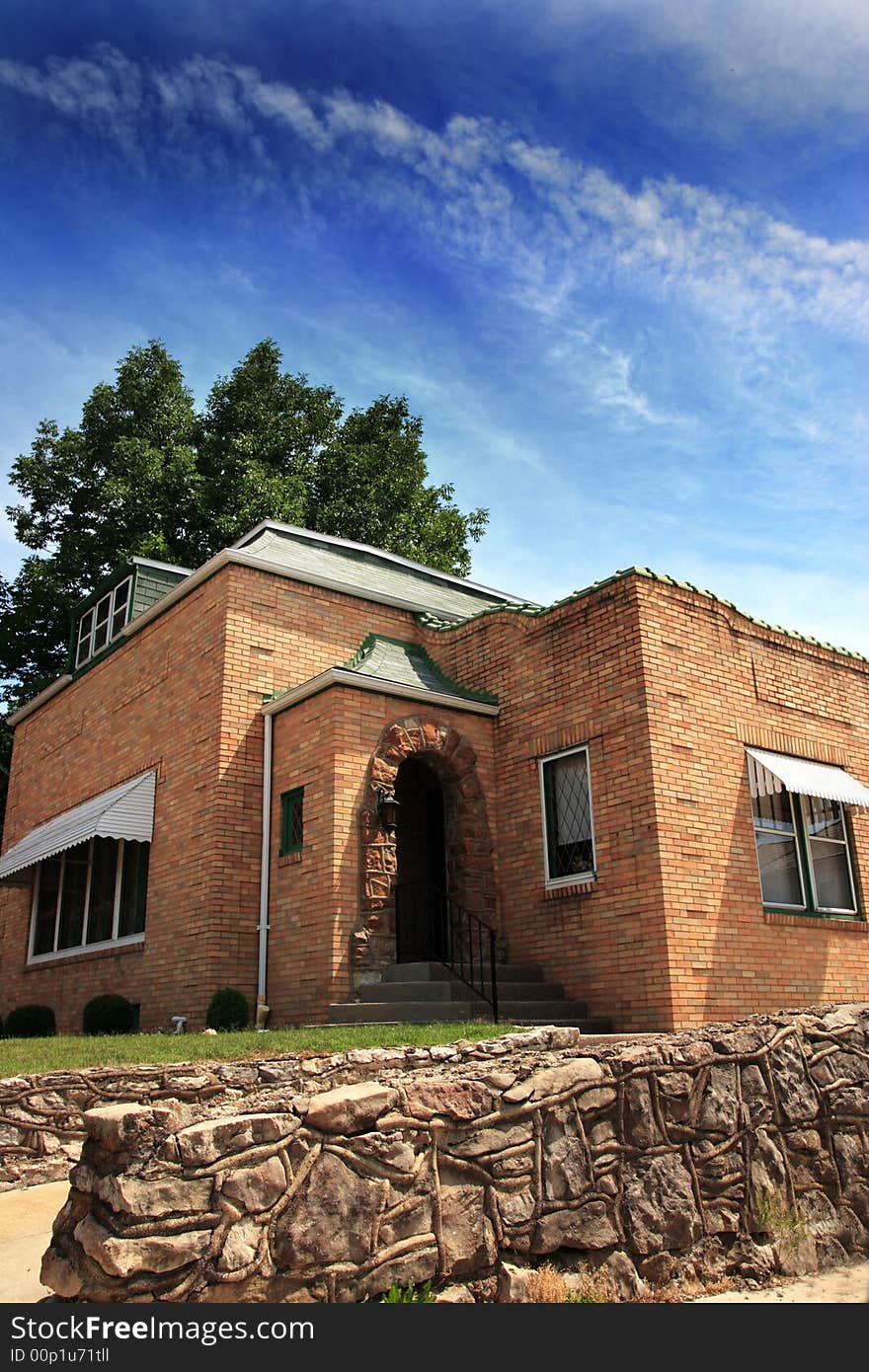 Brick house with stone wall and vivid blue sky.