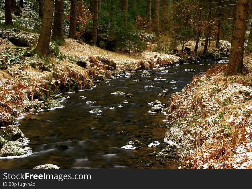 Landscape with motion blurred river and partly snow covered forest. Landscape with motion blurred river and partly snow covered forest.