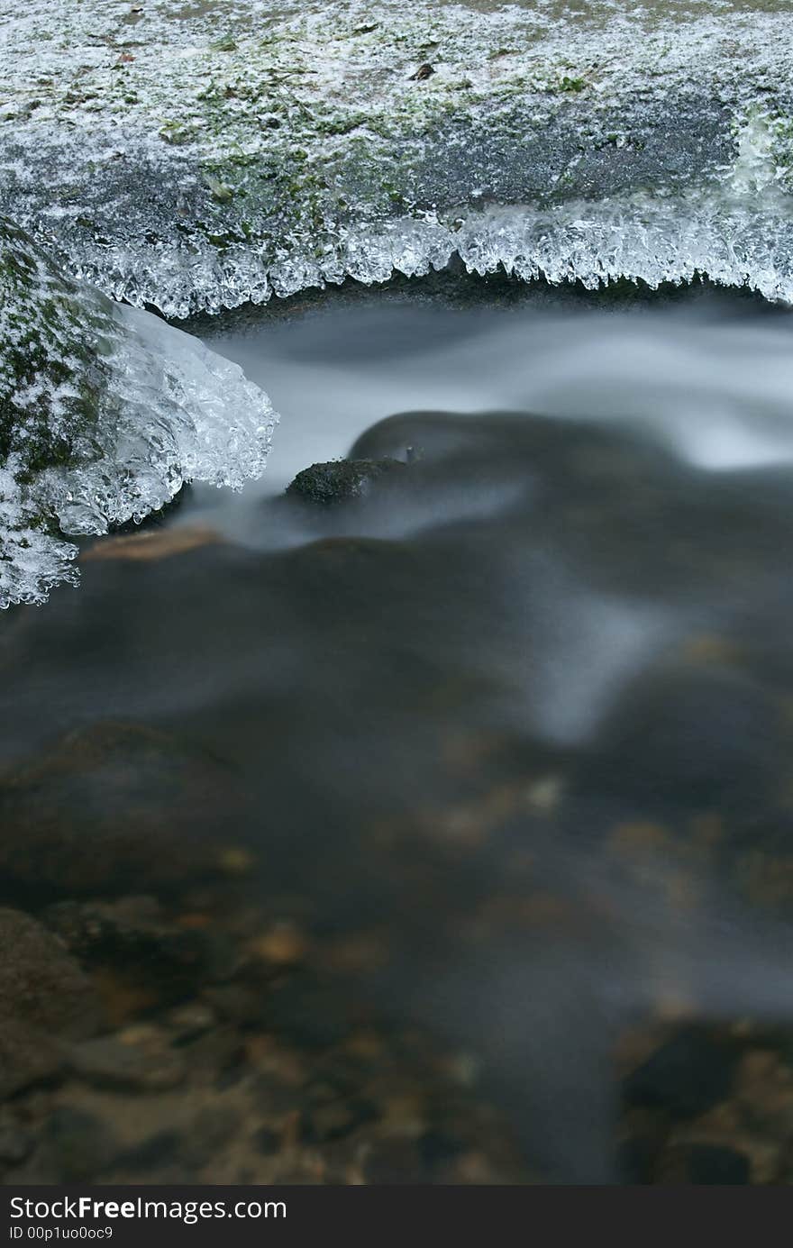 Motion blurred winter stream with detail of frozen stones