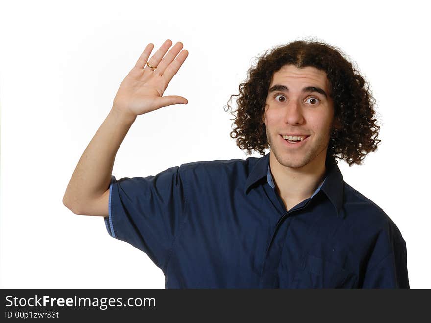 Young man with curly hair and blue shirt raising hand in 'high five' or tentative wave, isolated on white. Young man with curly hair and blue shirt raising hand in 'high five' or tentative wave, isolated on white