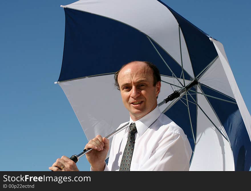 Businessman on the beach in business attire with a white and blue umbrella and a beautiful blue sky behind him, asking the question, do you have enough cover. Businessman on the beach in business attire with a white and blue umbrella and a beautiful blue sky behind him, asking the question, do you have enough cover