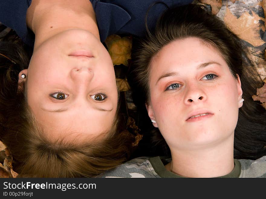 Two teenage girls lying on leaves with dreamy gaze upwards. Two teenage girls lying on leaves with dreamy gaze upwards