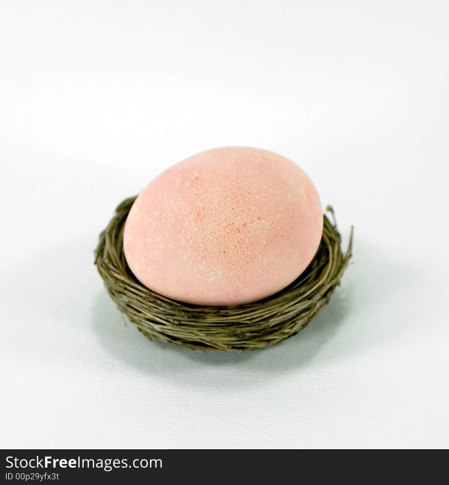 Light peach / orange / pink Easter egg in a nest. Light peach / orange / pink Easter egg in a nest