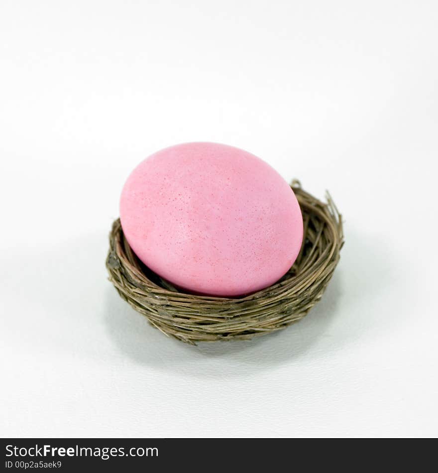 Pastel pink Easter egg in a nest.