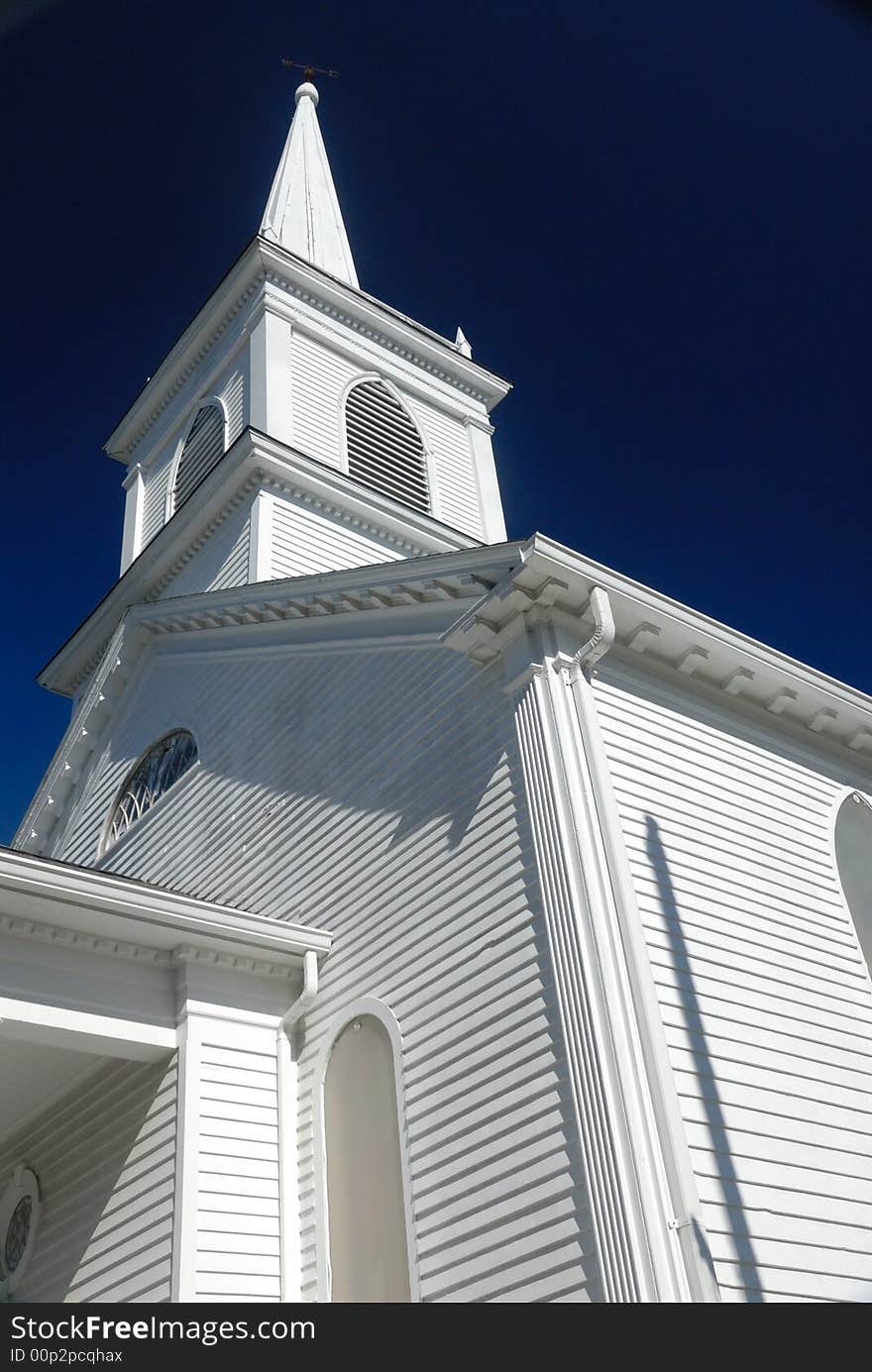 Wooden church spire against deep blue sky, vertical