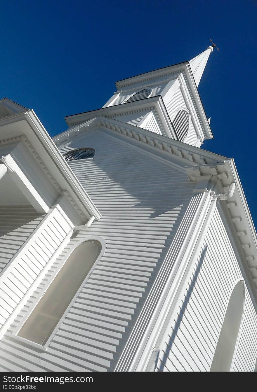 Wooden church spire against deep blue sky, vertical