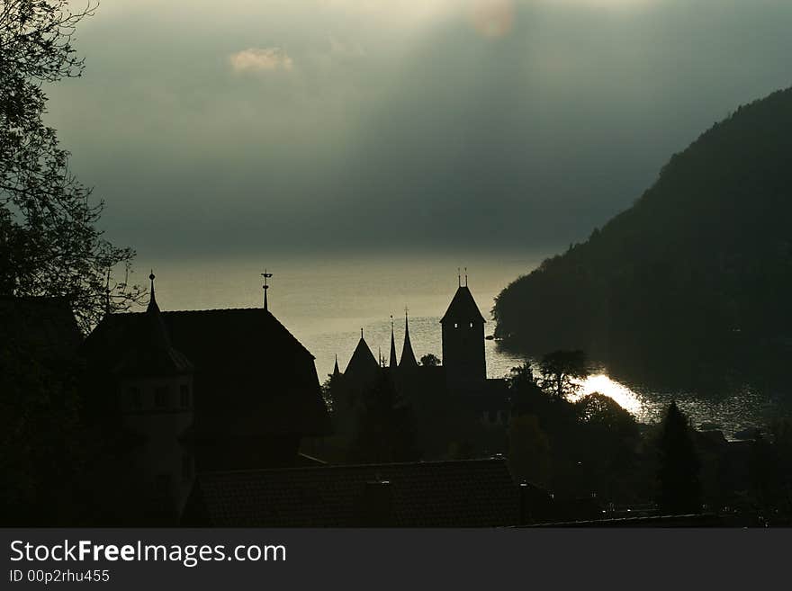 A castle tower silhouetted against a shimmering lake in the early morning. A castle tower silhouetted against a shimmering lake in the early morning