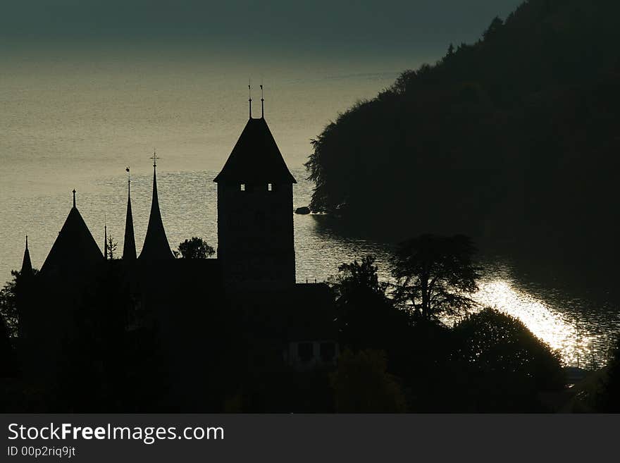 A castle tower silhouetted against a shimmering lake in the early morning. A castle tower silhouetted against a shimmering lake in the early morning