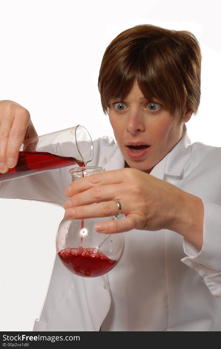 Worried young lady scientist in white coat, pouring liquid, isolated on white - humorous concept. Worried young lady scientist in white coat, pouring liquid, isolated on white - humorous concept