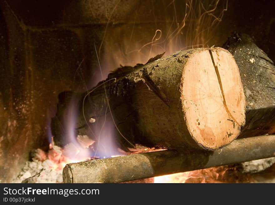 Fireplace with a big trunk burning and incandescent ash in movement.