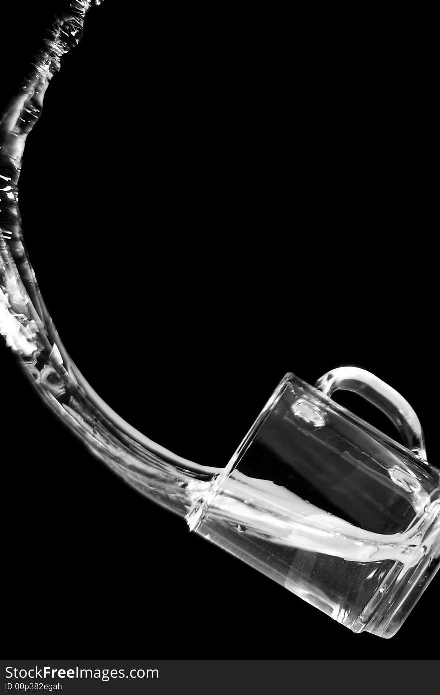 Water pours out from a glass. Black background