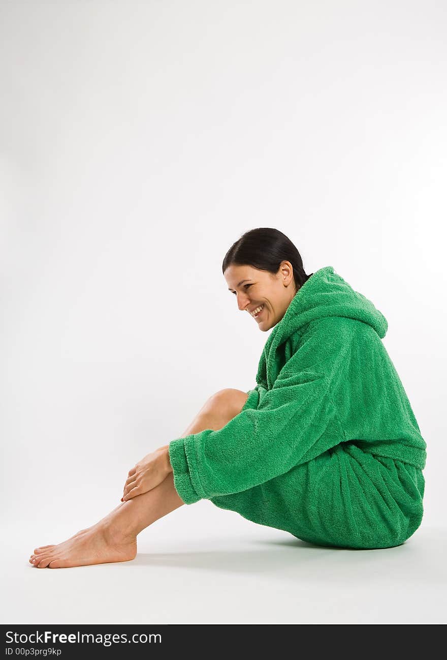 Sitting smiling woman in green bathrobe on white background. Sitting smiling woman in green bathrobe on white background