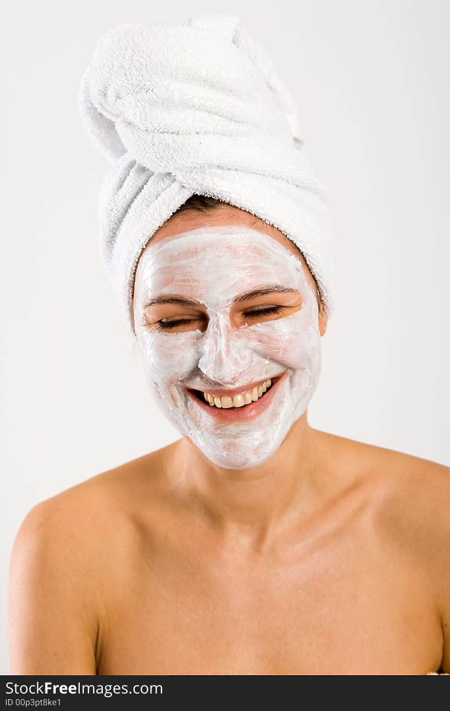 Nice woman laughing with closed eyes. With facemask and towel on head. Nice woman laughing with closed eyes. With facemask and towel on head.