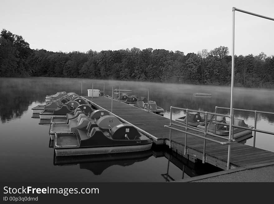 Paddle boats docked on misty lake black and white. Paddle boats docked on misty lake black and white