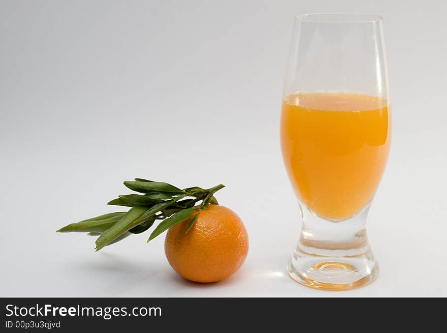 A glass of tanderine juice and fruit on white background