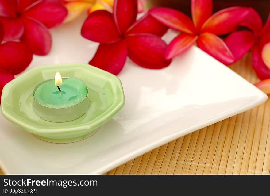 Aromatic candle and tropical red frangipanis. Aromatic candle and tropical red frangipanis
