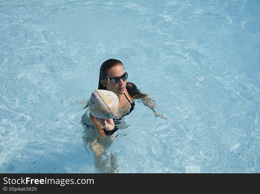 Young caucasian woman playing a game in the pool with her friends. Young caucasian woman playing a game in the pool with her friends