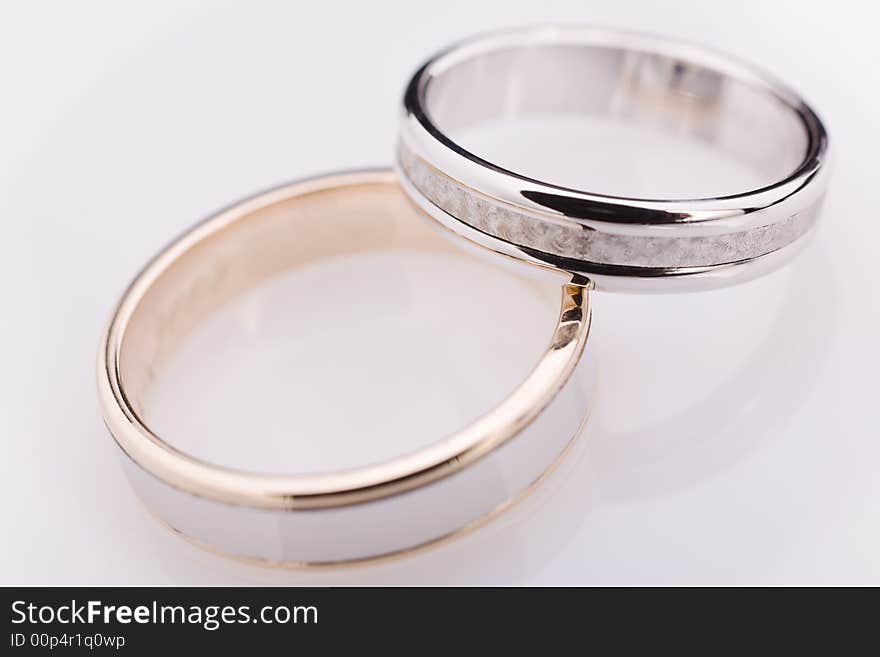 Two white gold engagement rings over a white reflective background