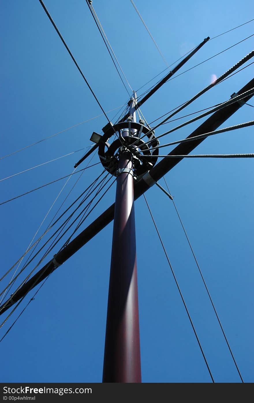 Crow's nest on an old wooden ships Mast shot from below against bright blue