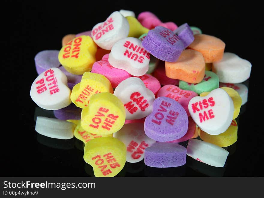 Pile of valentine candy hearts reflected in a mirror on black background. Pile of valentine candy hearts reflected in a mirror on black background.