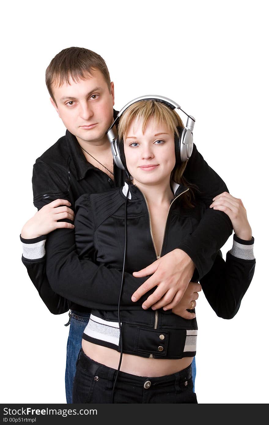 Young happy amorous couple with headphones at home listening to the music