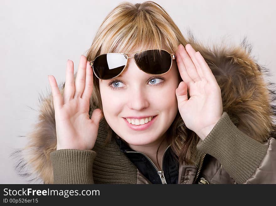 Playful girl with sunglasses in a jacket with a collar of fur