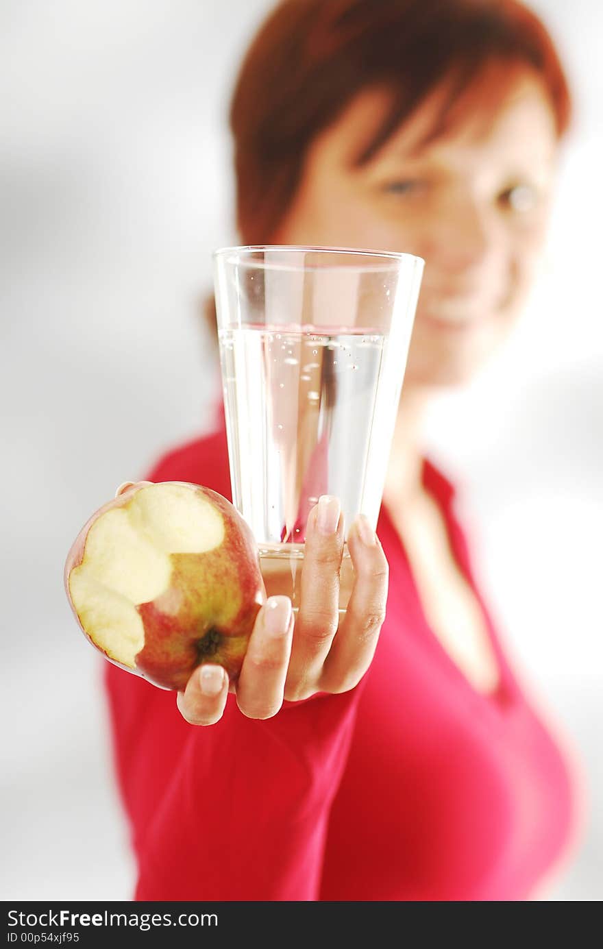 A woman with glass of water and apple. A woman with glass of water and apple