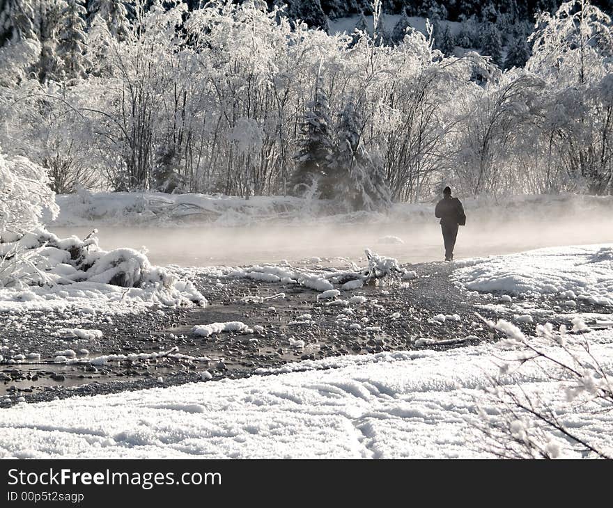 A lone figure at a snowy stream with mist. A lone figure at a snowy stream with mist