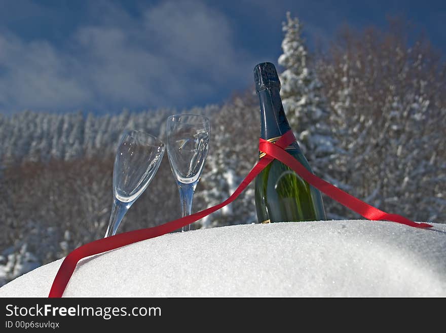 Glasses and bottle of champagne in snow