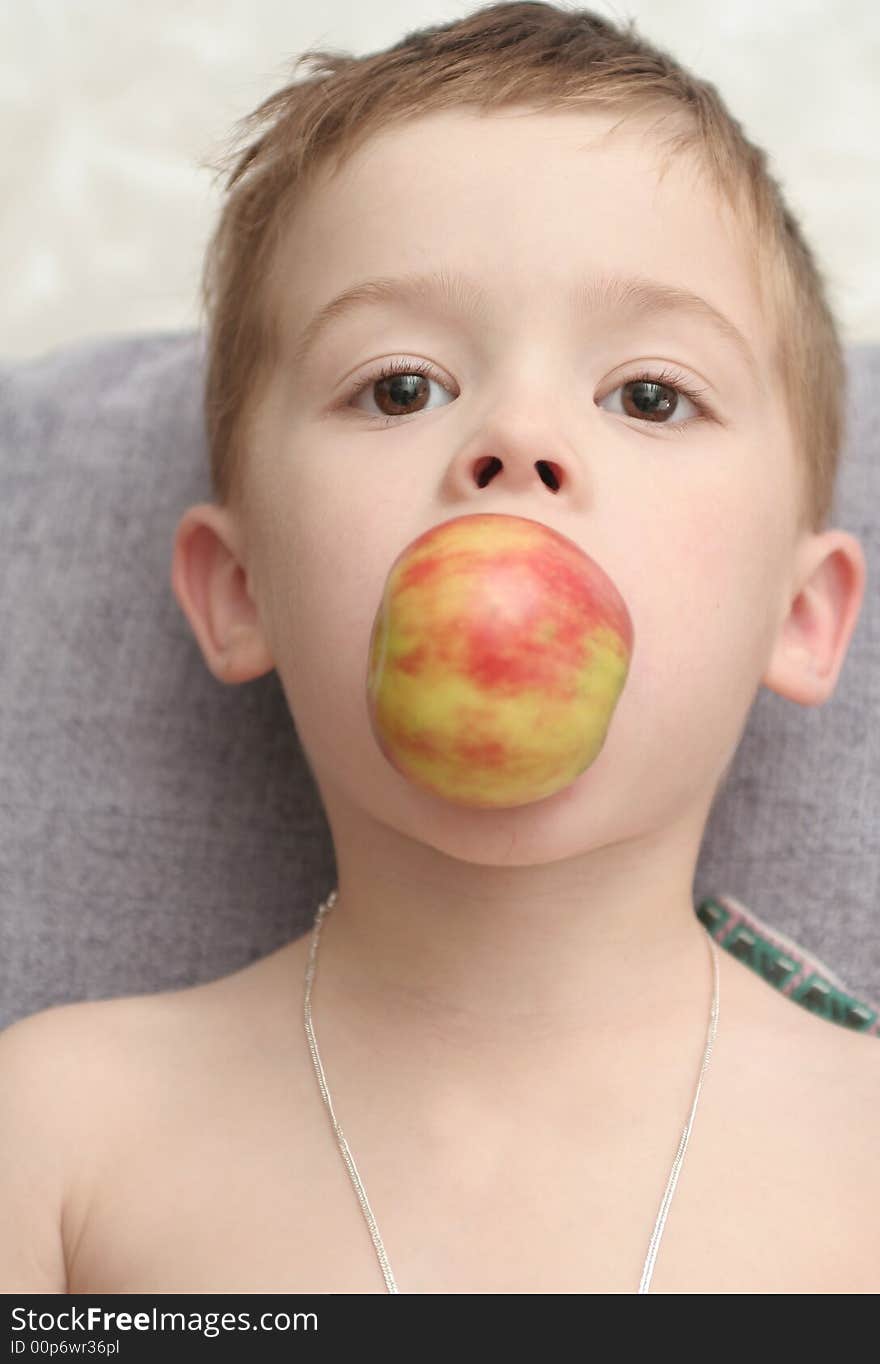 The boy which holds an apple a mouth