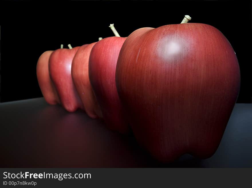 Red plastic apples over mirror and selective focus