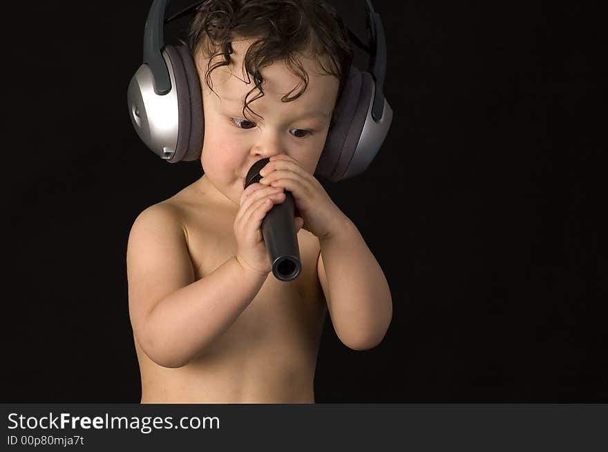 Sing baby with headphone and microphones, on a black background. Sing baby with headphone and microphones, on a black background.